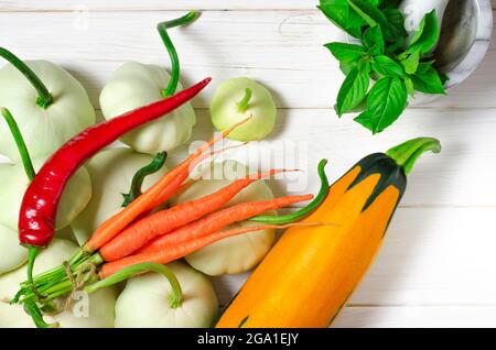 Ensemble de légumes : les carottes, les pâtisseries aux queues vertes et les courgettes multicolores se trouvent sur une vieille table en bois Banque D'Images