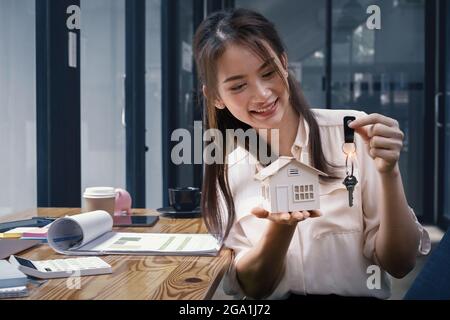 Un agent immobilier démontre le modèle de la Maison aux clients intéressés par l'achat d'une assurance maison. Le concept de l'assurance habitation ou automobile et Banque D'Images