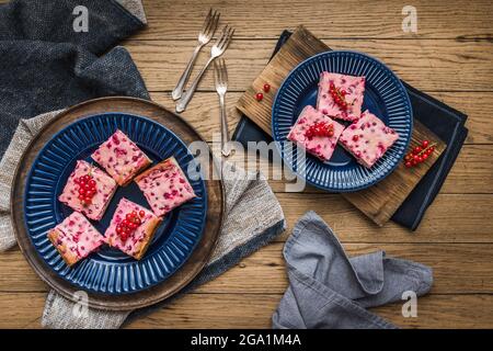 Morceaux de tarte crémeuse au cassis sur des assiettes bleues sur fond de bois, vue du dessus Banque D'Images