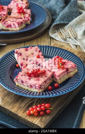 Morceaux de tarte crémeuse au cassis sur une assiette bleue sur fond en bois, à la verticale Banque D'Images