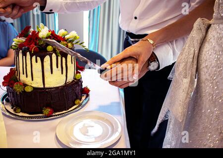 Les jeunes mariés coupent le gâteau de mariage. La mariée et le marié au mariage ont coupé un gâteau de mariage Banque D'Images