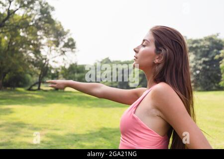 jeune adolescente en bonne santé qui s'étire des bras et ferme les yeux pour se détendre après avoir terminé l'exercice dans le parc de la ville le dimanche matin. vie Banque D'Images