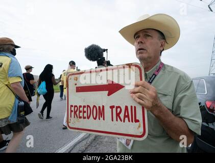 Georgetown, États-Unis. 28 juillet 2021. Les militants des droits de vote nationaux et texans, y compris cet homme portant un panneau « Freedom Trail », commencent une marche de quatre jours de 30 miles de Georgetown, au Texas, au Capitole de l'État à Austin. En raison de la chaleur estivale du Texas, plusieurs quarts de travail de 100 personnes feront des marches d'environ 4 milles chacun. La Marche pour la démocratie appelle à l'adoption de la loi John Lewis sur les droits de vote et à l'élimination des obstacles au vote à l'échelle de l'État. Crédit : Bob Daemmrich/Alay Live News Banque D'Images