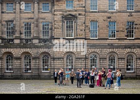 Un groupe de touristes se rassemblent sur la place du Parlement dans la vieille ville d'Édimbourg lors d'une visite à pied. Banque D'Images