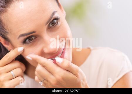 Une jeune femme met des lentilles de contact dans ses yeux. Banque D'Images