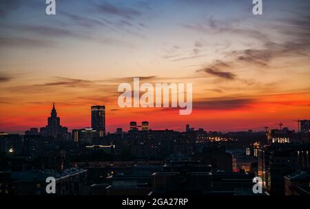 Coucher de soleil rouge et bleu avec nuages dans la ville. Silhouette de bâtiments et de grues. Horizon de la grande ville. Moscou, Russie. Banque D'Images
