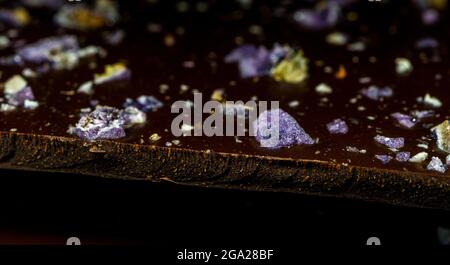 Meilleure tuile de chocolat noir avec pistache et violet. Arrière-plan noir, gros plan. Photo de haute qualité Banque D'Images