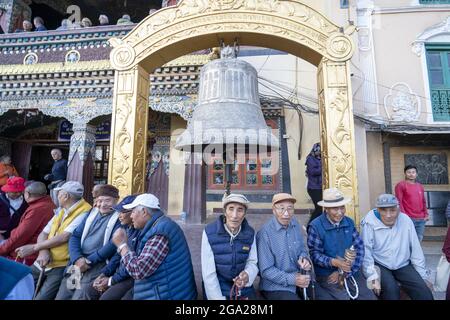 Les gens assis autour d'une cloche dans la cour de la plus grande stupa bouddhiste tibétaine au Népal à Boudhanath à Katmandou, Népal Banque D'Images