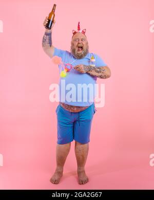 FAT Happy man agit comme un bébé heureux mais boit de la bière Banque D'Images