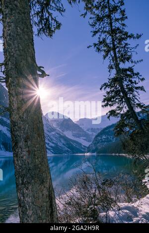 Lac Louise et une rafale de soleil au-dessus des montagnes enneigées du parc national Banff; Alberta, Canada Banque D'Images