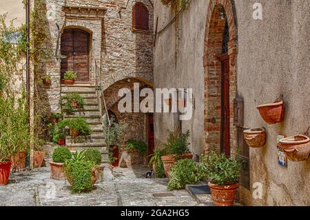 Extérieur d'un ancien bâtiment en pierre avec un escalier et trois entrées pour des appartements séparés avec pots de fleurs en terre cuite sur la terrasse ainsi... Banque D'Images