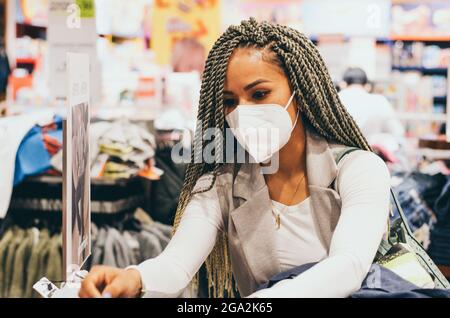 Belle femme avec des tresses et un masque de protection sur son visage antivirus. Concept de protection contre les virus dans les industries de la mode, de la beauté et du shopping. Banque D'Images