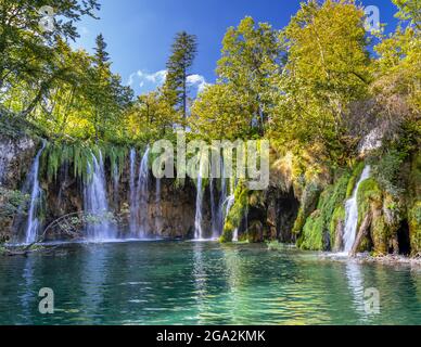 Le ciel bleu et les arbres entourent les chutes d'eau de l'un des lacs immaculés de Plitvice; le parc national des lacs de Plitvice, Croatie Banque D'Images