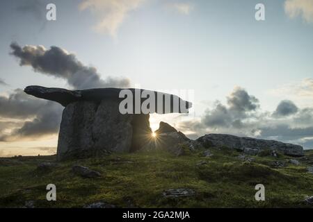 Le portail du dolmen tombeau de Poulnabrone avec le soleil levant qui brille à travers les pierres mégalithiques sur le Burren; Comté de Clare, Irlande Banque D'Images