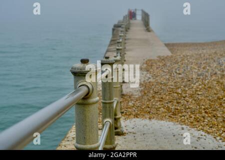 Un paysage de front de mer brumeux et brumeux au stade de Hastings, dans l'est du Sussex, en Angleterre, avec son cadre métallique victorien bordant les plages Banque D'Images