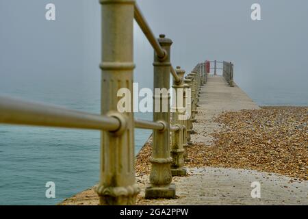 Un paysage de front de mer brumeux et brumeux au stade de Hastings, dans l'est du Sussex, en Angleterre, avec son cadre métallique victorien bordant les plages Banque D'Images