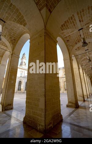 Vue sur le clocher de la cathédrale de Lecce à travers les colonnes sous le portique en face des bâtiments entourant la Piazza del Duomo à Lecce Banque D'Images