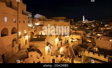 Panorama nocturne de la ville des anciennes habitations troglodytiques avec le clocher de la cathédrale de Matera surplombant la ville ; Matera, Basilicate, Italie Banque D'Images