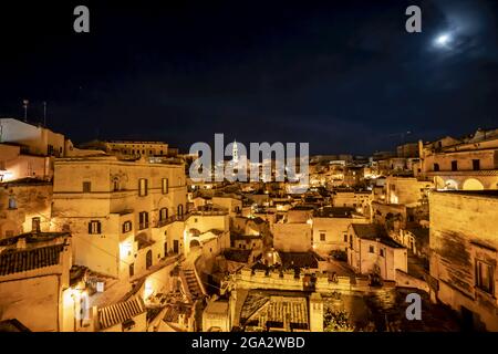 Panorama nocturne de la ville des anciennes habitations troglodytiques avec le clocher de la cathédrale de Matera surplombant la ville ; Matera, Basilicate, Italie Banque D'Images