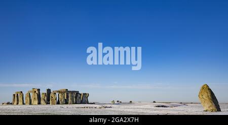 Stonehenge défini par la neige tôt le matin avec un ciel bleu vif et la Pierre de talon penchée à droite du cercle de pierre Banque D'Images