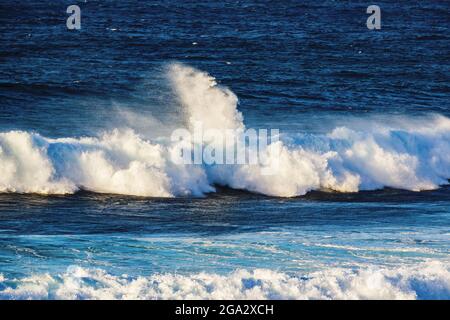 Paysage de vagues se brisant d'un belvédère au parc de la plage de Ho'okipa, avec une vue sur la côte au loin et un ciel nuageux près de Paia Banque D'Images