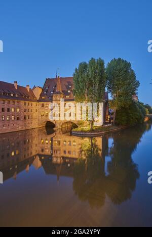 La rivière Pegnitz traverse Nuremberg à l'heure bleue avec le Heilig-Geist-Spital (Hôpital Saint-Esprit) dans la vieille ville ; Franconie, Bavière, Allemagne Banque D'Images