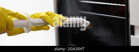 Homme en gants jaunes, lave-linge four avec vadrouille à vapeur, gros plan Banque D'Images