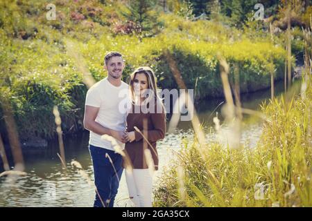 Portrait d'un mari et d'une femme à l'extérieur près d'un ruisseau dans un parc municipal en automne; Edmonton, Alberta, Canada Banque D'Images