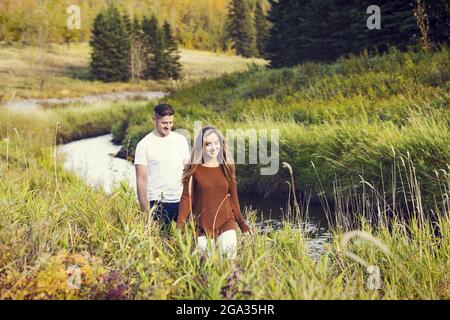 Mari et femme passent du temps ensemble de qualité à l'extérieur près d'un ruisseau dans un parc de la ville; Edmonton, Alberta, Canada Banque D'Images