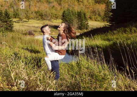 Mari et femme passent du temps ensemble de qualité à l'extérieur près d'un ruisseau dans un parc de la ville; Edmonton, Alberta, Canada Banque D'Images