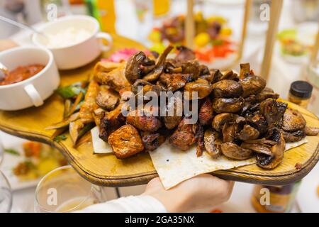 Assiette de viande frite sur charbon de bois avec épices sur un panneau de bois. Carré d'agneau, de porc, de kebab, de poulet, de champignons et de sauces tomate pour la viande Banque D'Images
