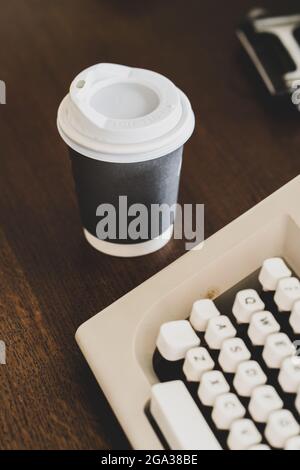 Photo verticale d'une machine à écrire vintage à côté d'une tasse de café en papier Banque D'Images