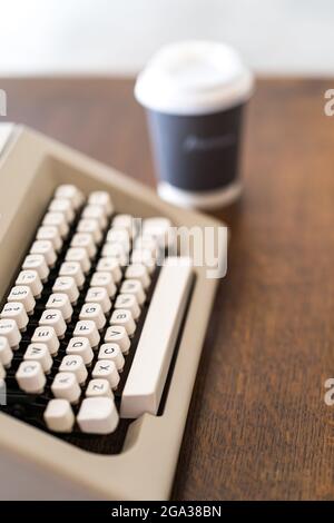 Photo verticale d'une machine à écrire vintage à côté d'une tasse de café en papier Banque D'Images