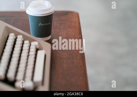 Gros plan d'une machine à écrire vintage à côté d'une tasse de café en papier Banque D'Images