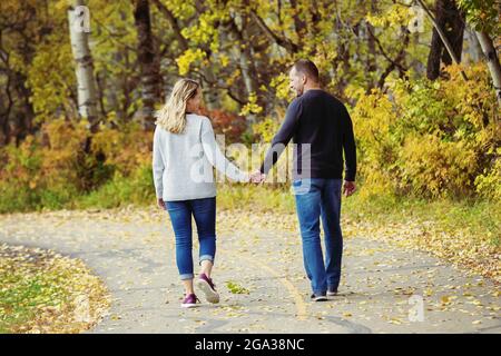 Un couple marié mature qui passe du temps ensemble de qualité à marcher à l'extérieur dans un parc de la ville pendant un après-midi d'automne chaud; St. Albert, Alberta, Canada Banque D'Images