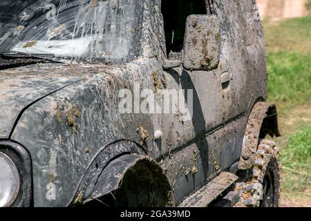 une voiture boueuse dans une couche de marais après un voyage tout-terrain, un gros plan d'une porte conducteur latérale avec rétroviseur et des seuils sur l'aile pour l'expédition conditi Banque D'Images