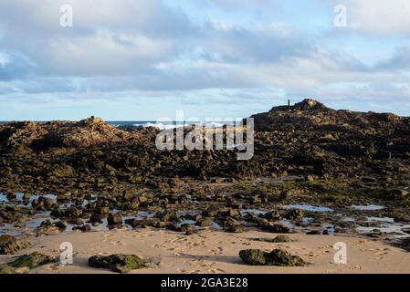 Ciel bleu et mer sur les rochers et le sable sur la plage. Les vagues se brisent sur les rochers et le sable sur la plage. Banque D'Images