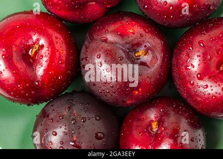 Vue de dessus des grands prunes rouges sur l'assiette verte. Banque D'Images