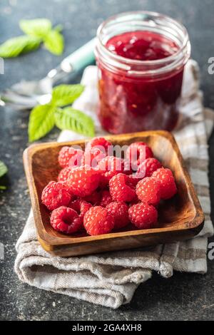 Framboises mûres dans un bol et confiture de framboises sur une serviette à carreaux. Banque D'Images