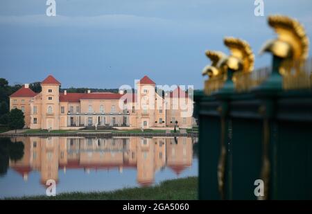 Rheinsberg, Allemagne. 28 juillet 2021. Château de Rheinsberg sur la rive est du lac Grienerick. Le château dans le quartier d'Ostprignitz-Ruppin appartient avec ses jardins à la Fondation Prusse des palais et des jardins Berlin-Brandebourg (SPSG). Sur la droite, on peut voir les casques dorés sur la clôture autour de l'obélisque. L'obélisque dans la ligne de vue du palais a été érigé en l'honneur du deuxième fils du roi soldat et de 28 participants à la guerre de sept ans. Credit: Soeren Stache/dpa-Zentralbild/dpa/Alay Live News Banque D'Images