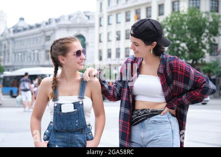 Deux femmes sympa souriant et regardant l'une l'autre. Deux amies qui se posent dans la rue. Banque D'Images