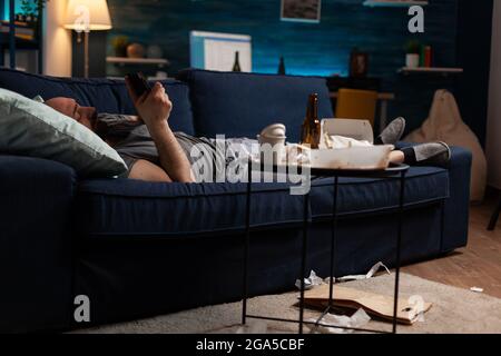 Triste malheureux malheureux seul déprimé déprimant homme surfant sur le smartphone, luttant avec la santé mentale passant par une dépression majeure. Angoissés et frustrés, les hommes lisant un avis de banque numérique Banque D'Images