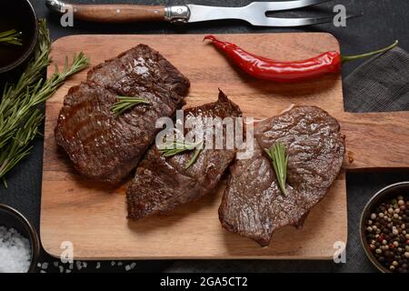 Steak de bœuf grillé juteux au romarin, viande frite, gros plan. Top Blade steaks sur bois Banque D'Images