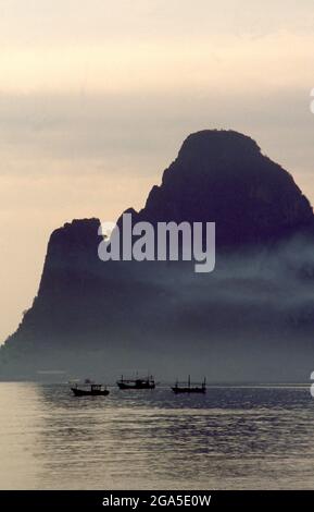 Thaïlande: Bateaux de pêche tôt le matin sur Ao Prachuap (baie de Prachuap), Prachuap Khiri Khan. En termes historiques, Prachuap est l'un des sept points d'atterrissage où les troupes impériales japonaises ont pris d'assaut à terre en 1941, sur leur chemin vers le sud pour occuper Malaya et Singapour. La ville est entourée par des montagnes de calcaire accidentées, dont Khao Chong Krajok, ou « montagne du tunnel miroir », est percée d’une ouverture naturelle qui ne ressemble pas à un miroir géant, et qui est peut-être le plus célèbre monument naturel de la ville. Banque D'Images