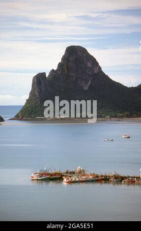 Thaïlande: Bateaux de pêche tôt le matin sur Ao Prachuap (baie de Prachuap), Prachuap Khiri Khan. En termes historiques, Prachuap est l'un des sept points d'atterrissage où les troupes impériales japonaises ont pris d'assaut à terre en 1941, sur leur chemin vers le sud pour occuper Malaya et Singapour. La ville est entourée par des montagnes de calcaire accidentées, dont Khao Chong Krajok, ou « montagne du tunnel miroir », est percée d’une ouverture naturelle qui ne ressemble pas à un miroir géant, et qui est peut-être le plus célèbre monument naturel de la ville. Banque D'Images