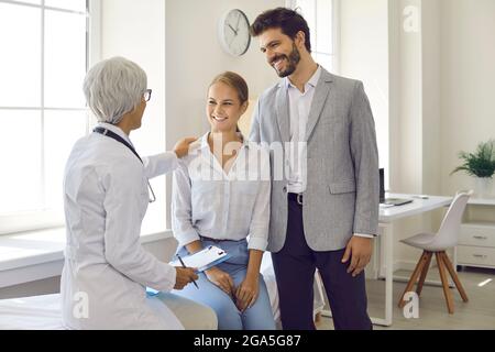 Un jeune mari et une femme heureux planifiant une grossesse et voyant un médecin de famille ensemble Banque D'Images