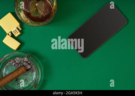 haut de la vue du cigare dans un cendrier près du verre de whisky sur la table de poker verte Banque D'Images