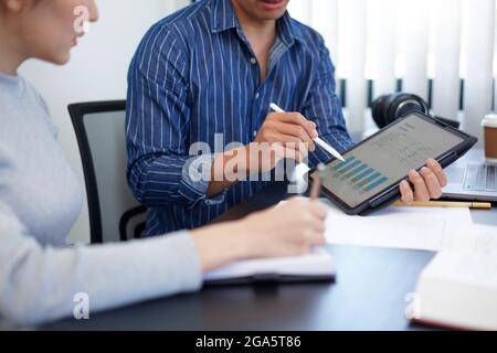 Concept de travail de bureau un homme d'affaires montrant un graphique à barres présentant des informations intéressantes sur une nouvelle tendance d'affaires à son collègue. Banque D'Images