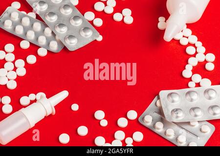 Pilules blanches débordant d'une bouteille blanche renversée sur fond rouge Banque D'Images