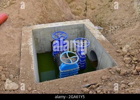 Les vannes à obturation à siège résilient relient la conduite d'alimentation en eau dans le bunker en béton sur le site de construction. Solutions pour l'eau potable et les eaux usées. Banque D'Images